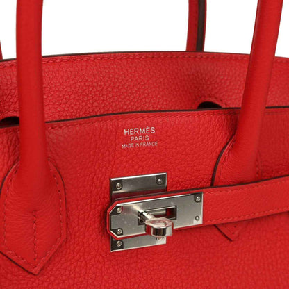 Elegant red leather handbag with silver hardware, featuring a timeless, sophisticated design.