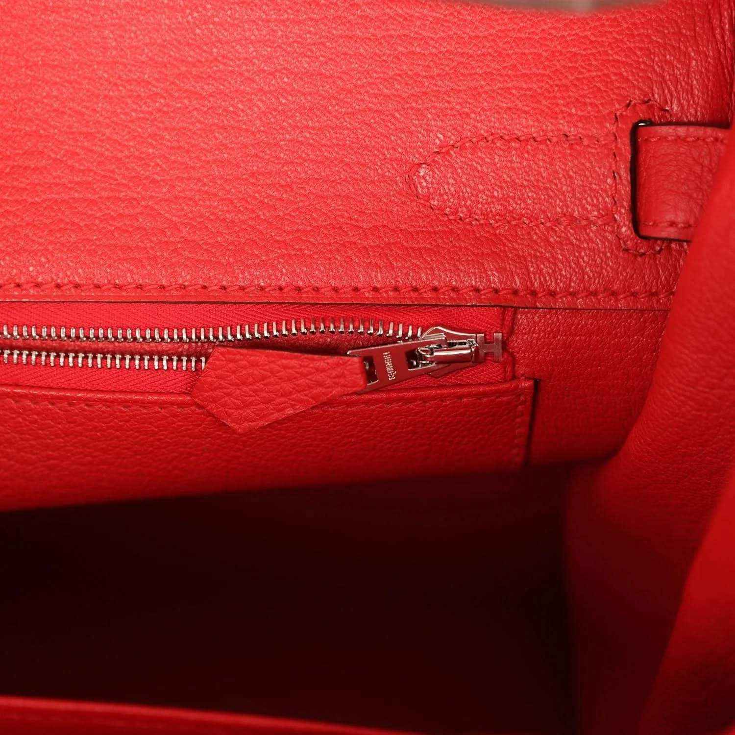 Elegant red leather handbag interior with silver zip, showcasing timeless craftsmanship.