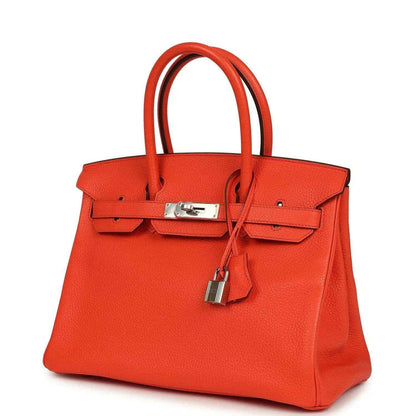 Timeless, elegant orange leather handbag with silver hardware and structured silhouette.