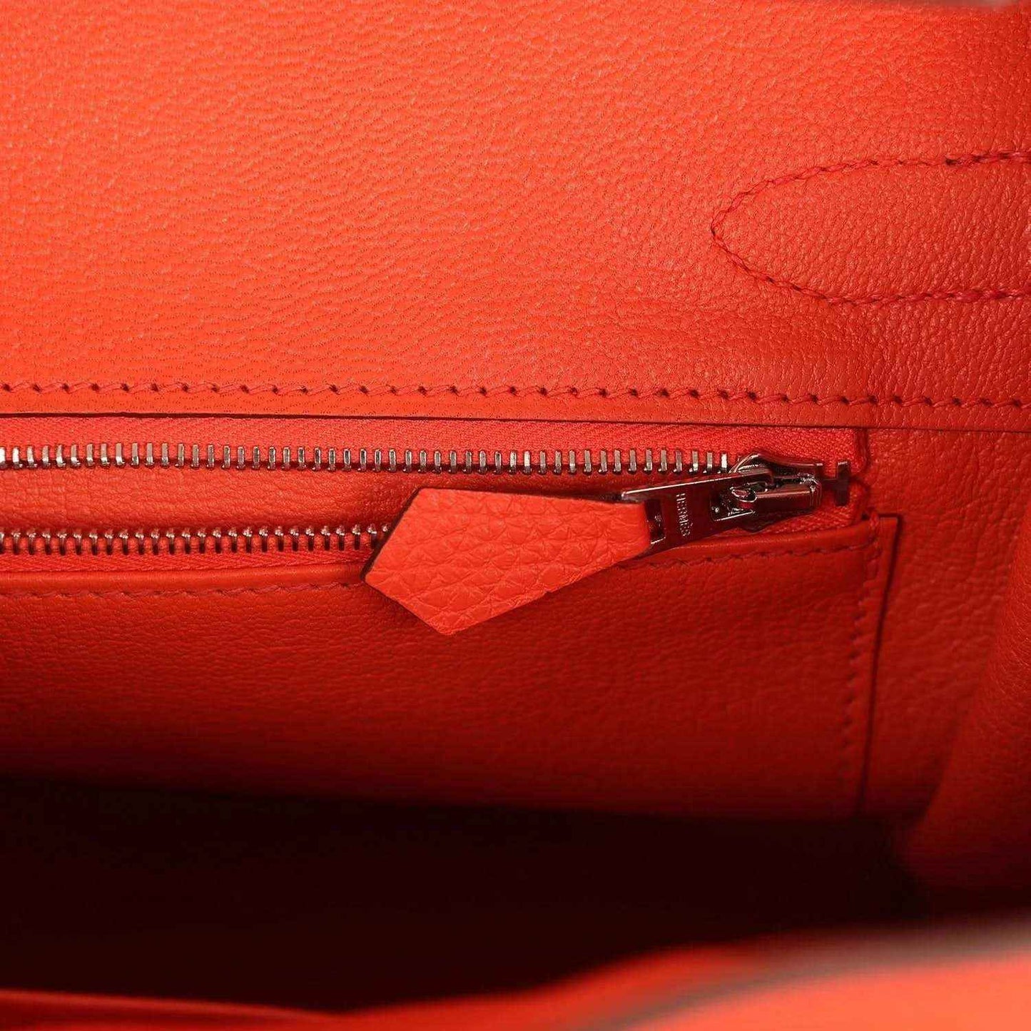 Timeless, elegant orange leather handbag interior with refined zip pocket detail.