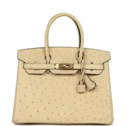 Timeless and elegant cream ostrich leather handbag with gold hardware and top handles.