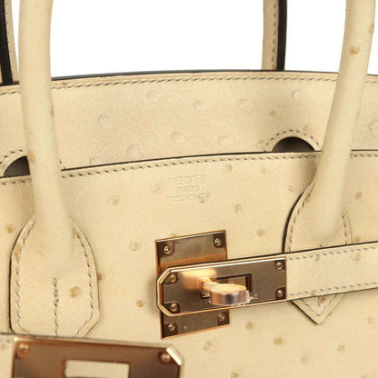 Elegant ivory leather handbag with gold-tone hardware and refined, timeless design.