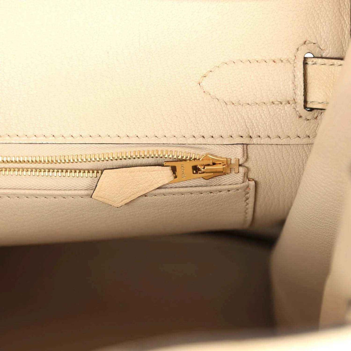 Elegant beige leather handbag interior with gold zipper, showcasing timeless sophistication.