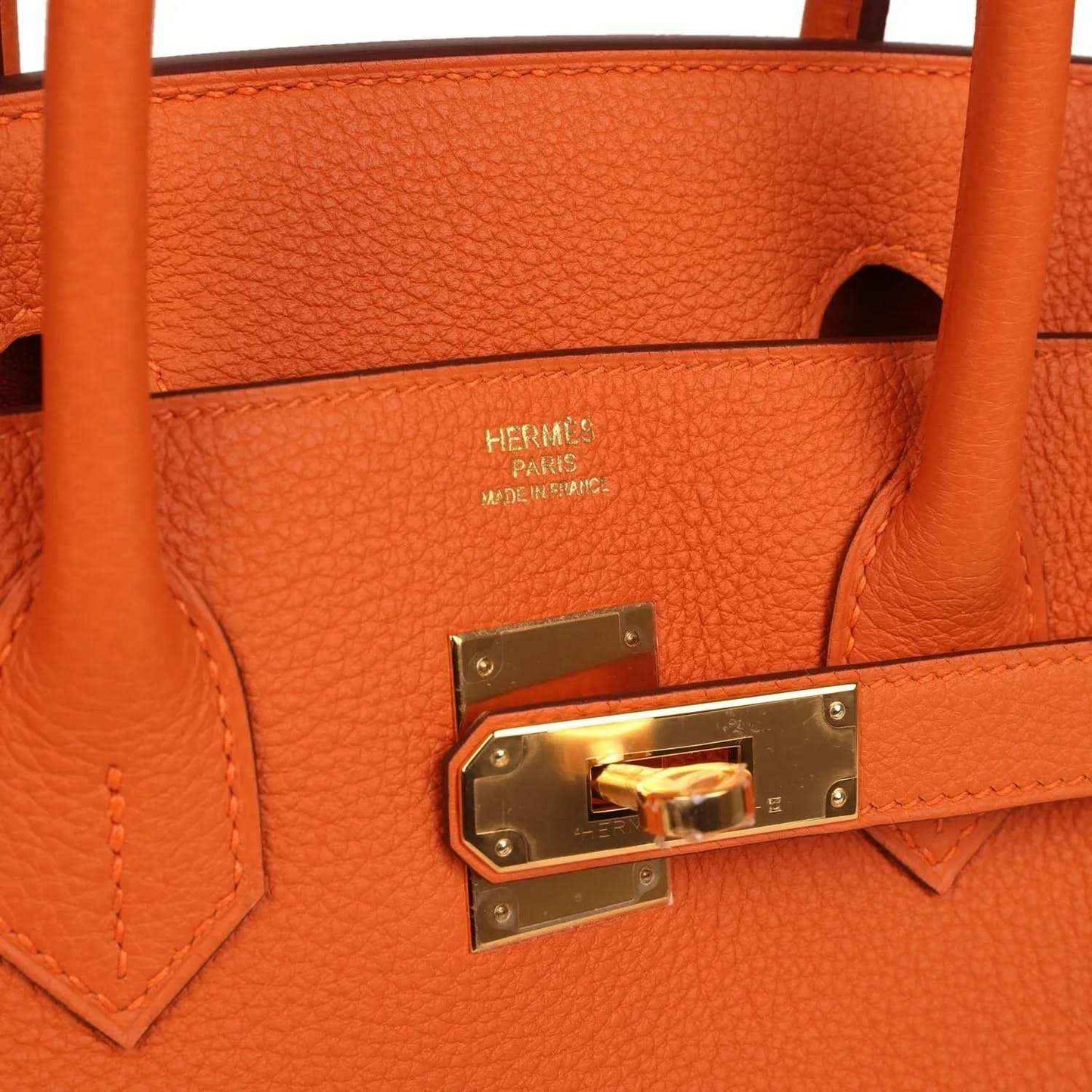 Timeless orange leather handbag with gold hardware and elegant, sophisticated design.