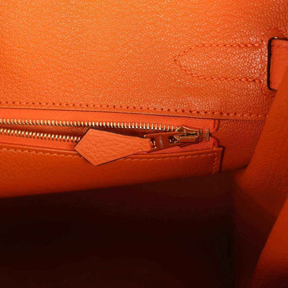 Elegant orange leather handbag interior with gold zipper detail, featuring refined stitching.