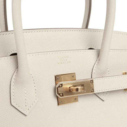 Elegant white leather handbag with gold hardware and double handles, timeless and sophisticated.