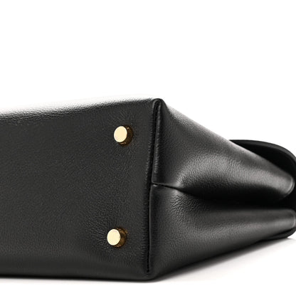 Black leather handbag corner with two gold studs and curved side panel
