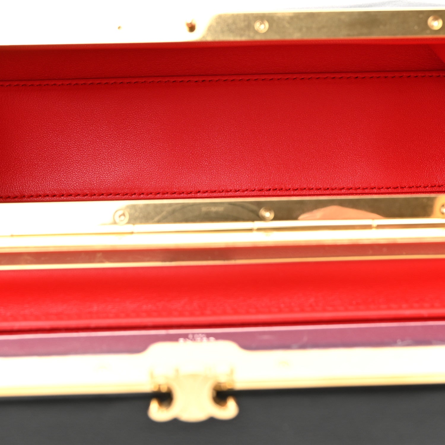 Black leather rectangle bag open to red interior lining with gold-tone clasp