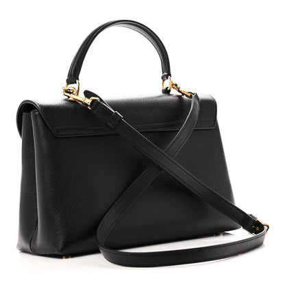 Black leather top-handle handbag with diagonal shoulder strap and gold-trim front flap