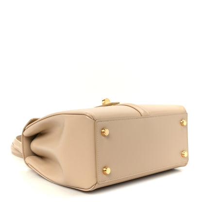 Small nude structured bag with front flap and gold-tone hardware, top closure