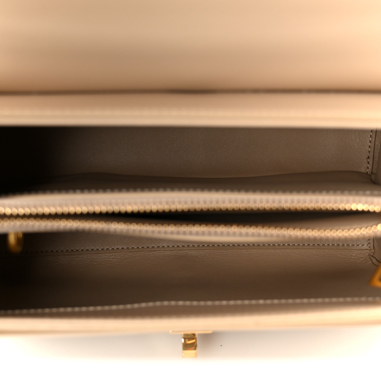 Nude leather bag interior with satin lining and zipper opening with gold trim