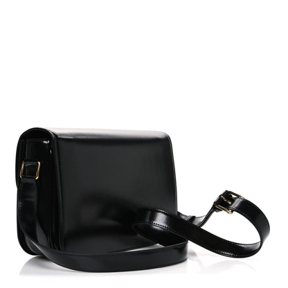 Shiny calfskin medium shoulder bag in black with front strap attachment and gold buckle