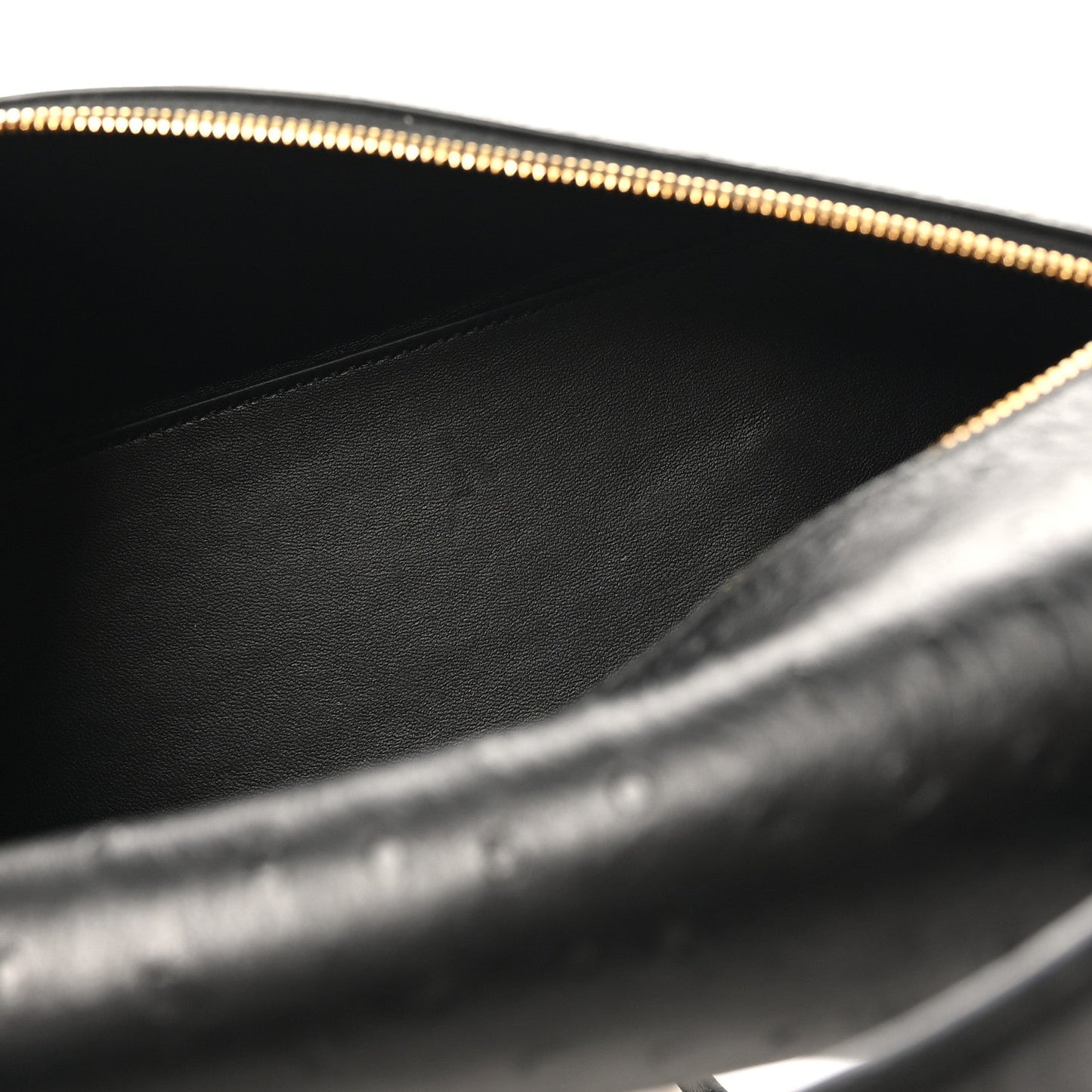 Black leather interior of ostrich bag with gold zipper trim and stitched lining.
