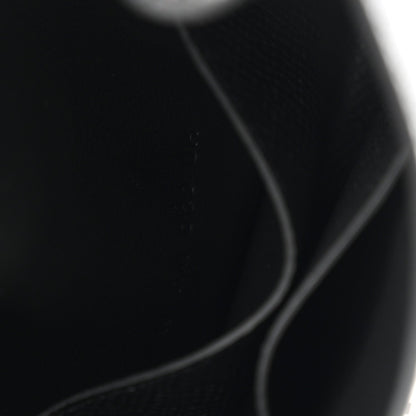 Black leather wallet corner with curved seam and edge stitching.