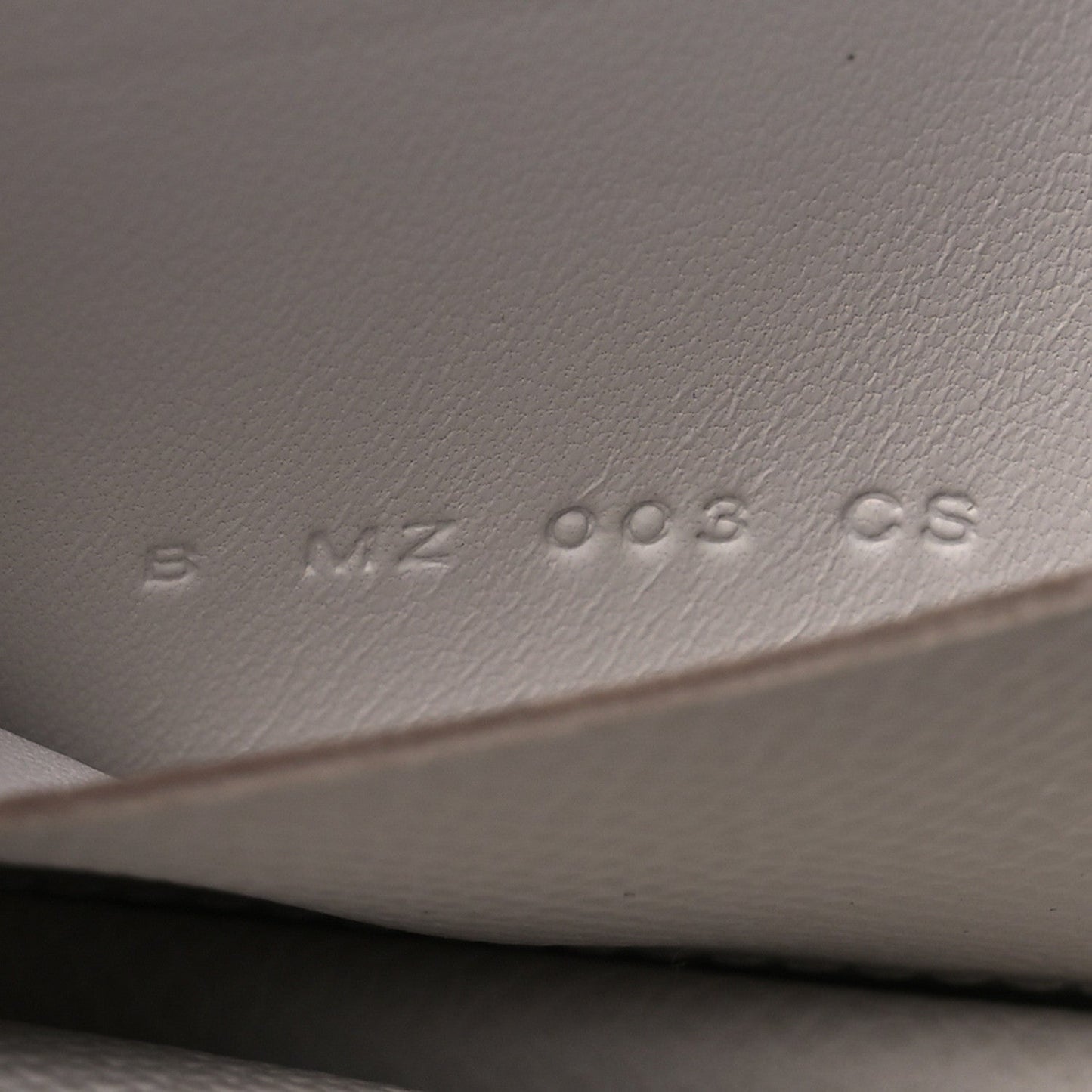 Embossed serial/markings on pale gray leather interior surface