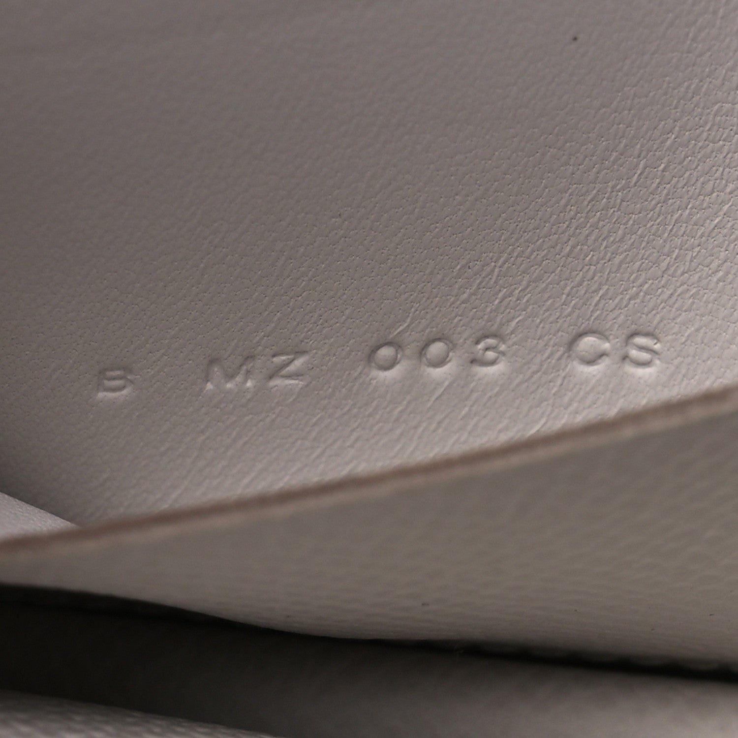 Embossed serial/markings on pale gray leather interior surface
