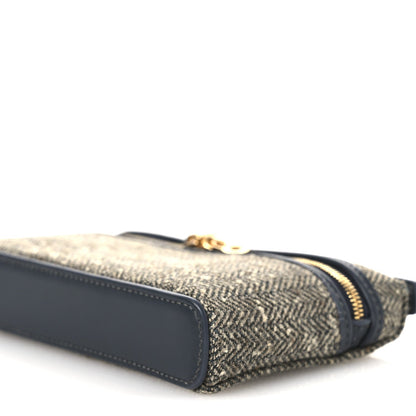 Mini herringbone pouch bottom corner with navy leather panel and gold zipper along edge