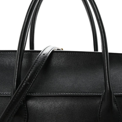 Black leather bag top handle with reinforced stitching detail.