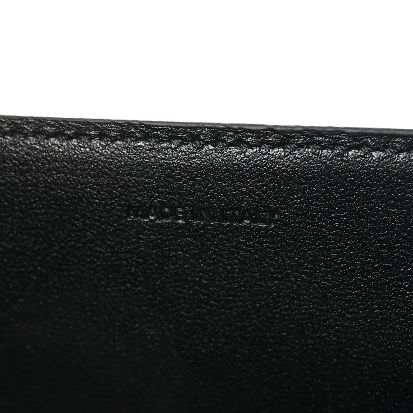 Black leather surface with subtle embossed mark on the bag