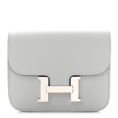 Hermes Constance slim wallet in light blue textured leather with front H clasp.