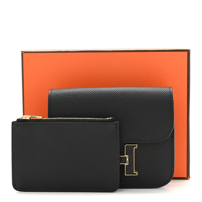 Black slim wallet with gold H clasp, shown with presentation box