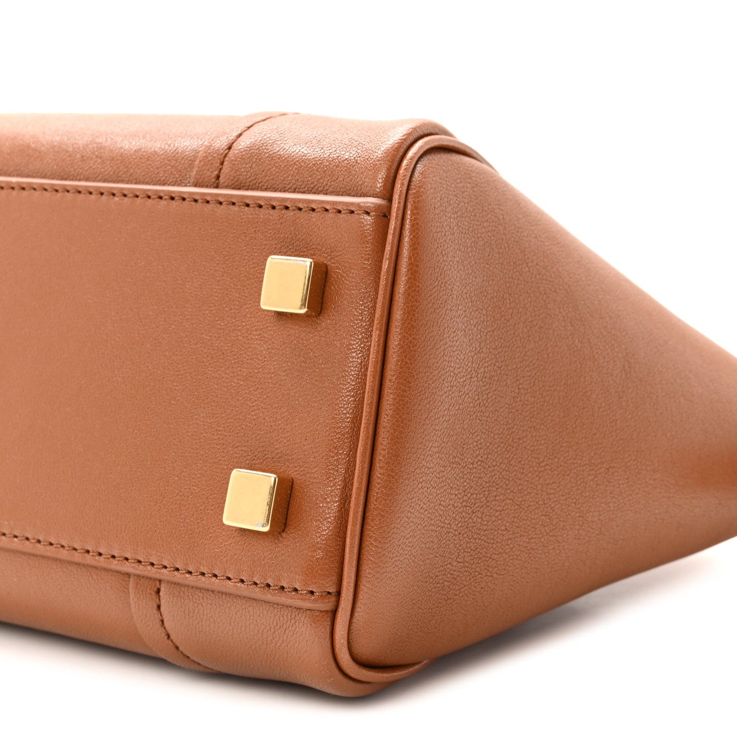 Tan leather tote corner with gold-tone studs and curved seam detail