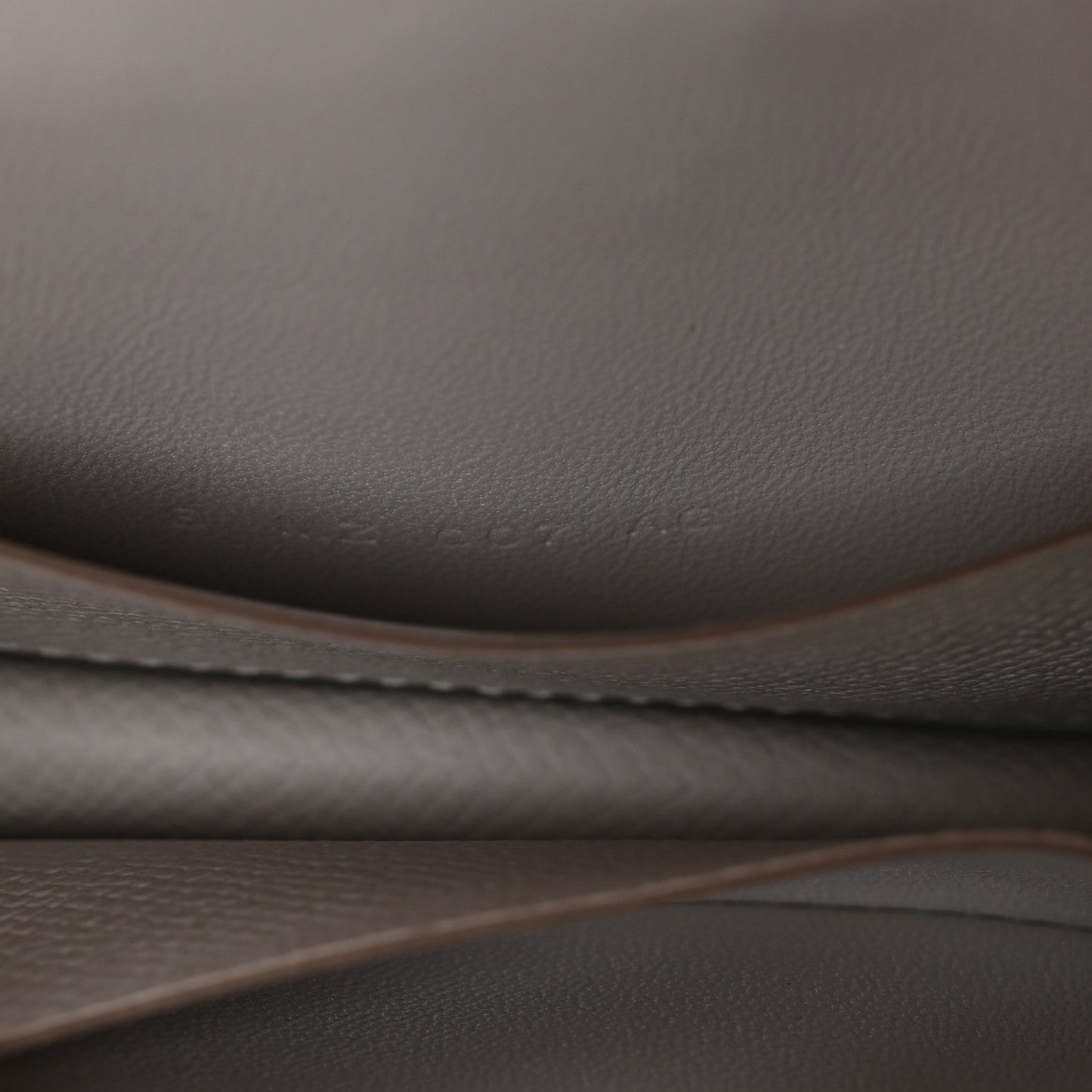 Pale gray leather edge and stitching detail on a slim wallet.