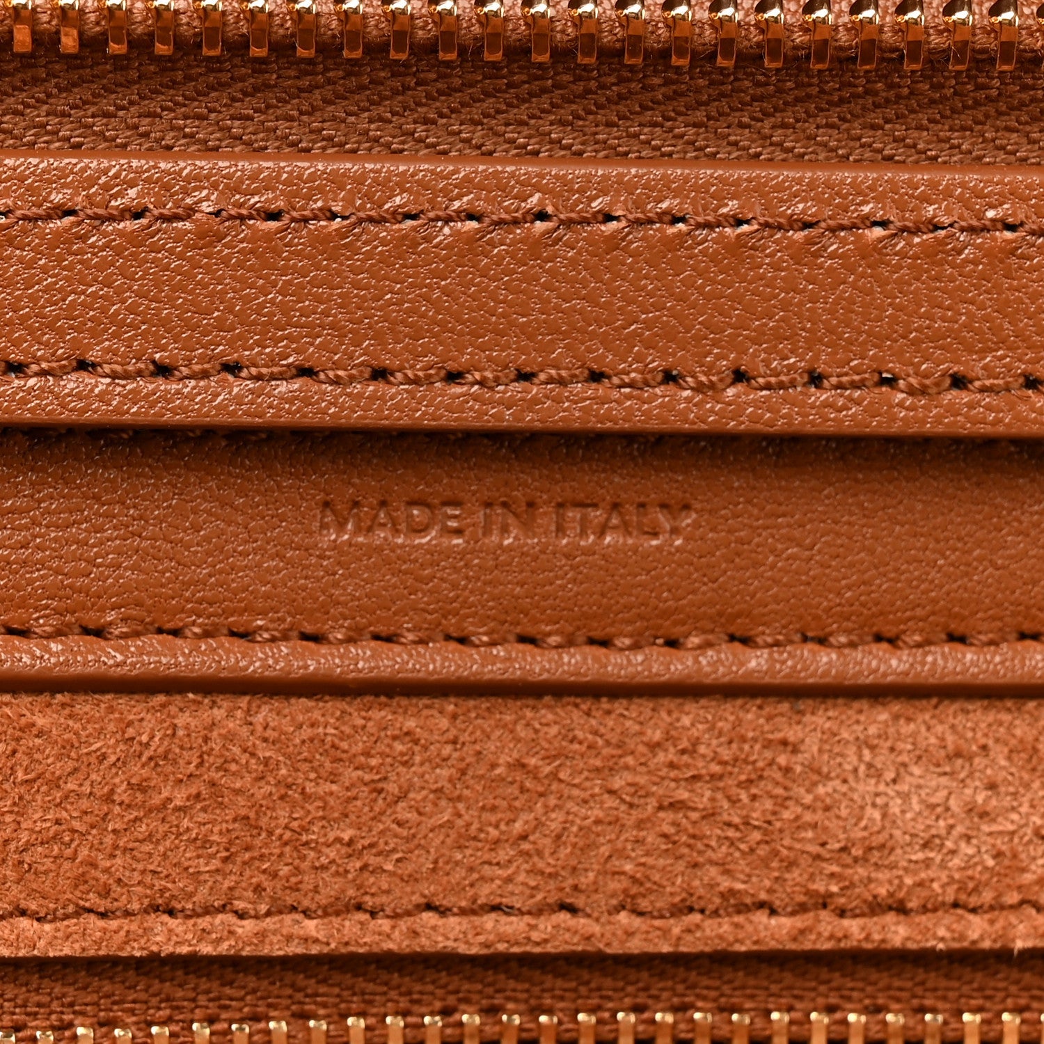 Tan leather handbag lining close-up with stitching and embossed label.