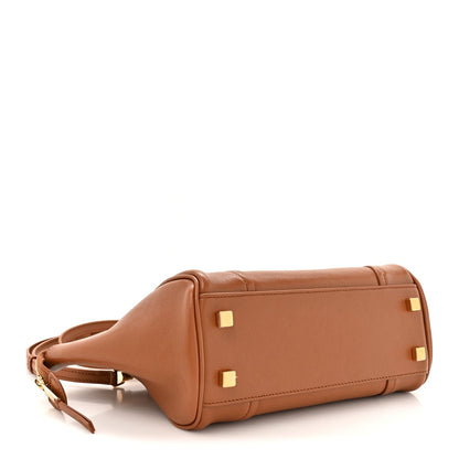 Tan leather small handbag with top handle and gold-tone feet on the base.
