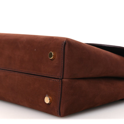 Chestnut brown leather bag corner with gold snap closure and side seam.