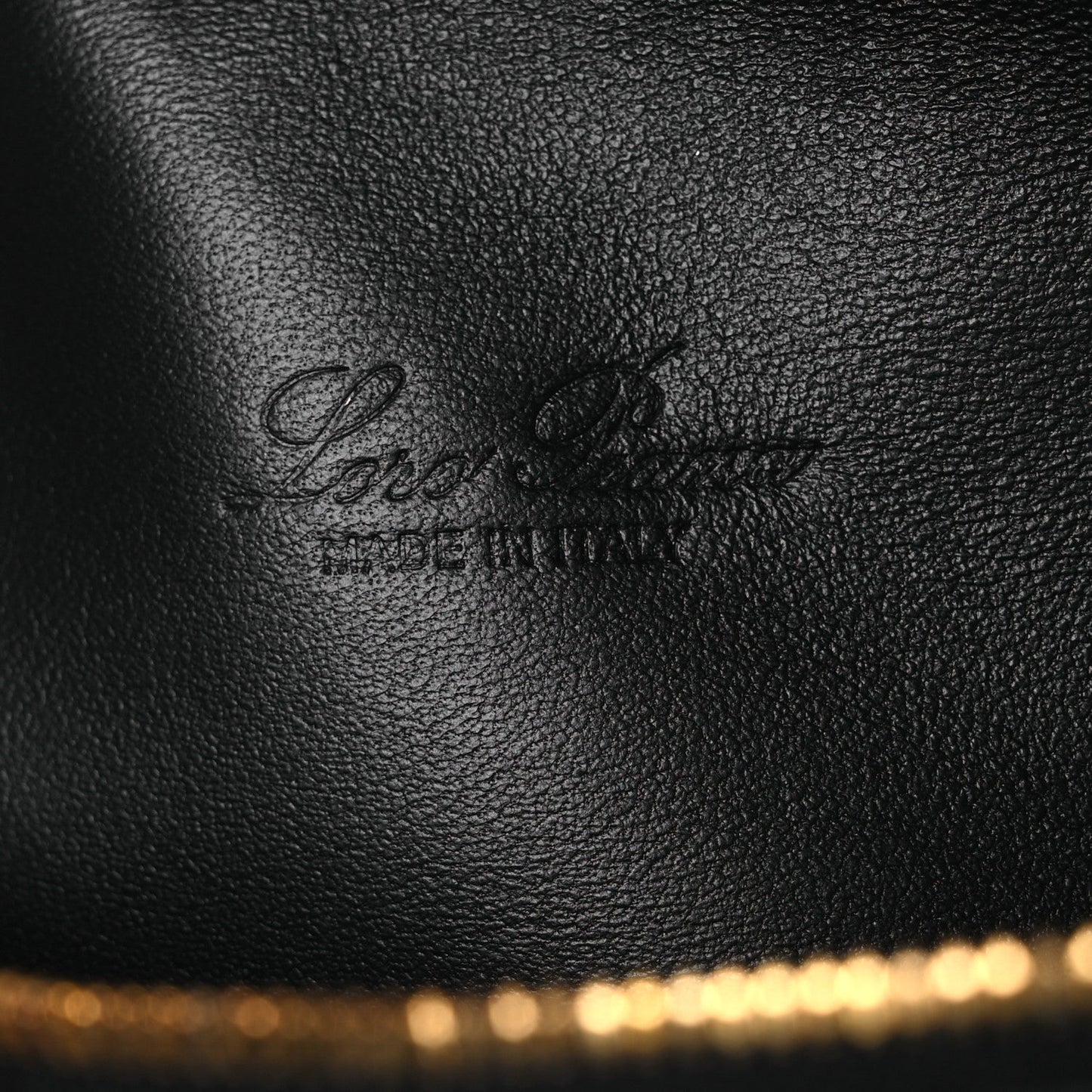Loro Piana engraved on black grained calfskin pouch surface near the gold zipper