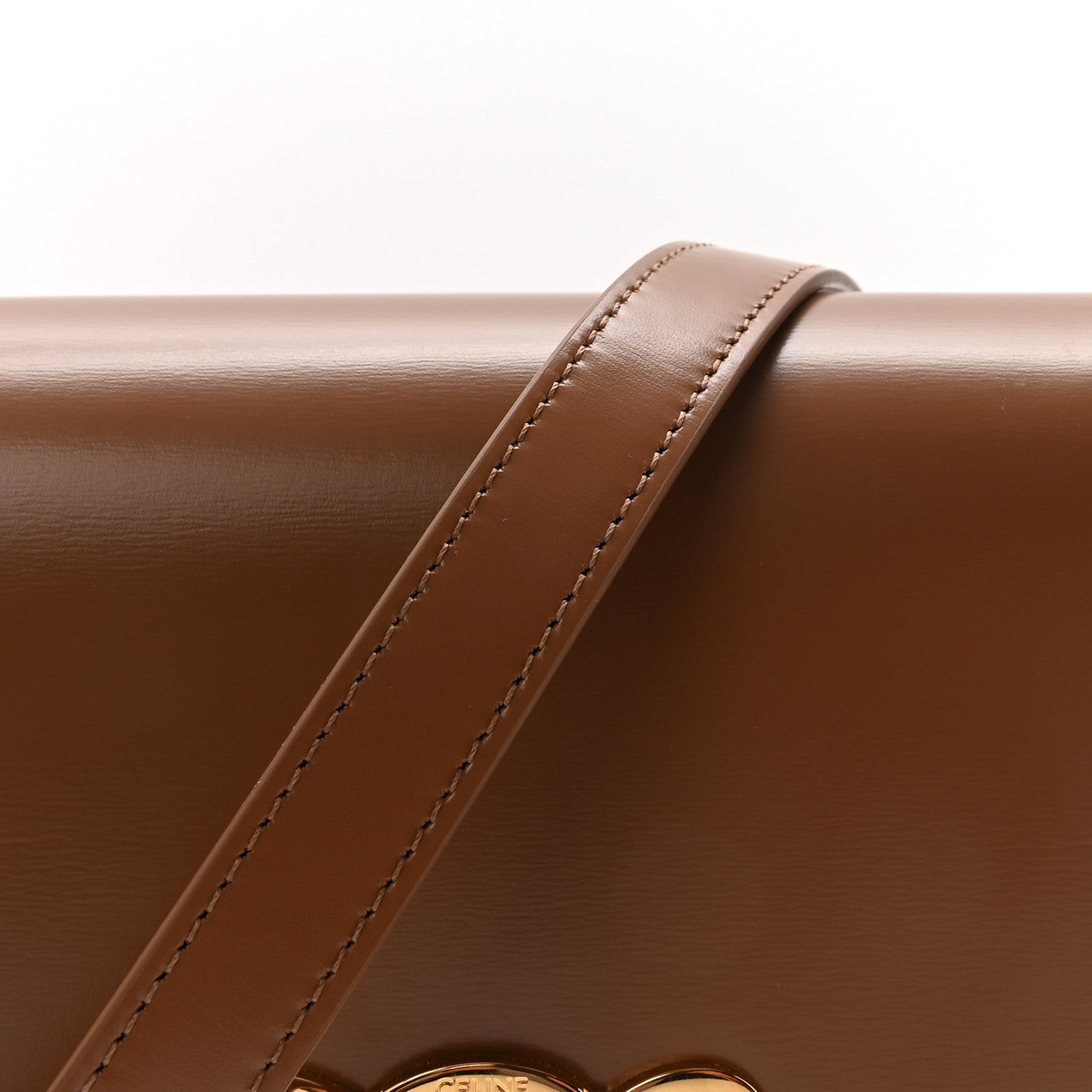 Calfskin crossbody strap with visible stitching and flap edge