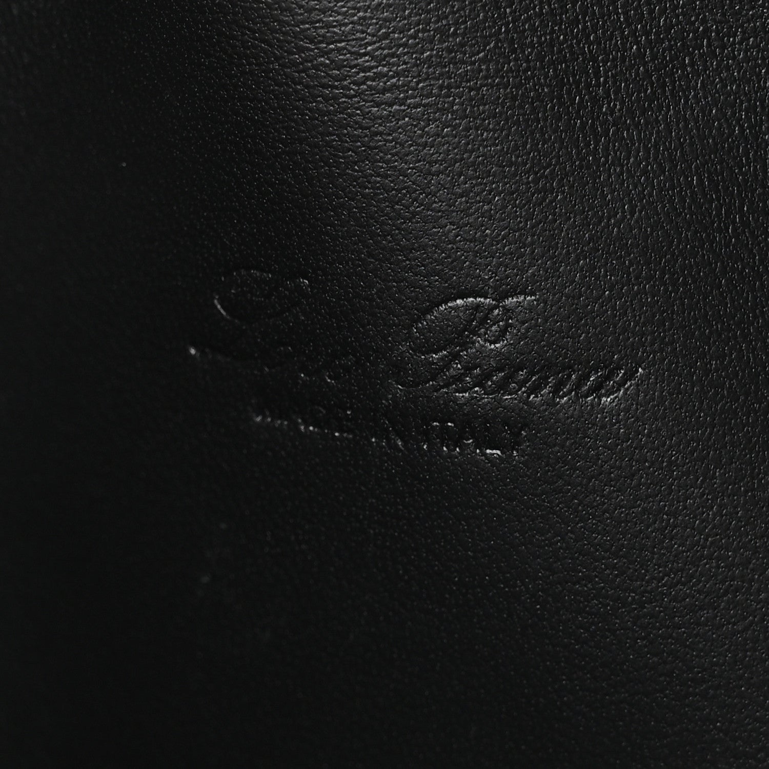 Close-up of black ostrich-textured leather pouch surface with subtle stitching
