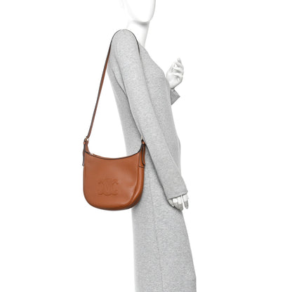 Tan leather small hobo shoulder bag worn crossbody with adjustable strap